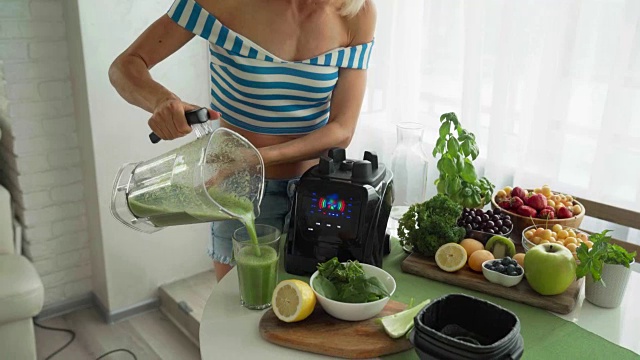 用搅拌机做绿色蔬菜奶昔的女人。健康的饮食生活方式视频素材