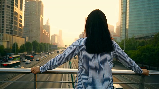 女人看着美丽的城市日落视频素材