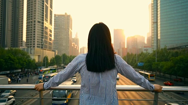 女人看着美丽的城市日落视频素材