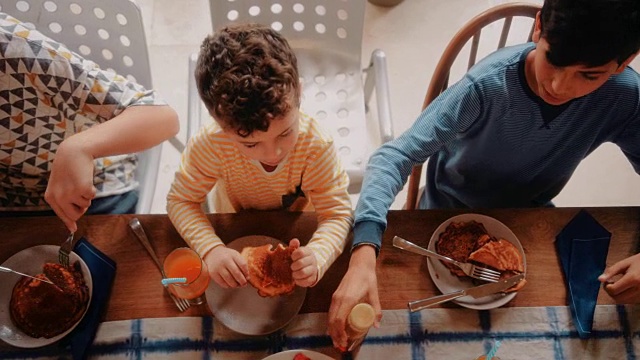 小男孩们围坐在厨房的桌子旁，一起吃早餐视频素材