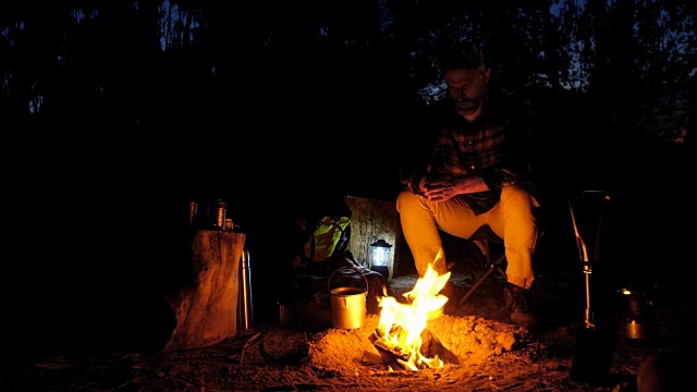 在森林里，一个人坐在篝火旁视频素材