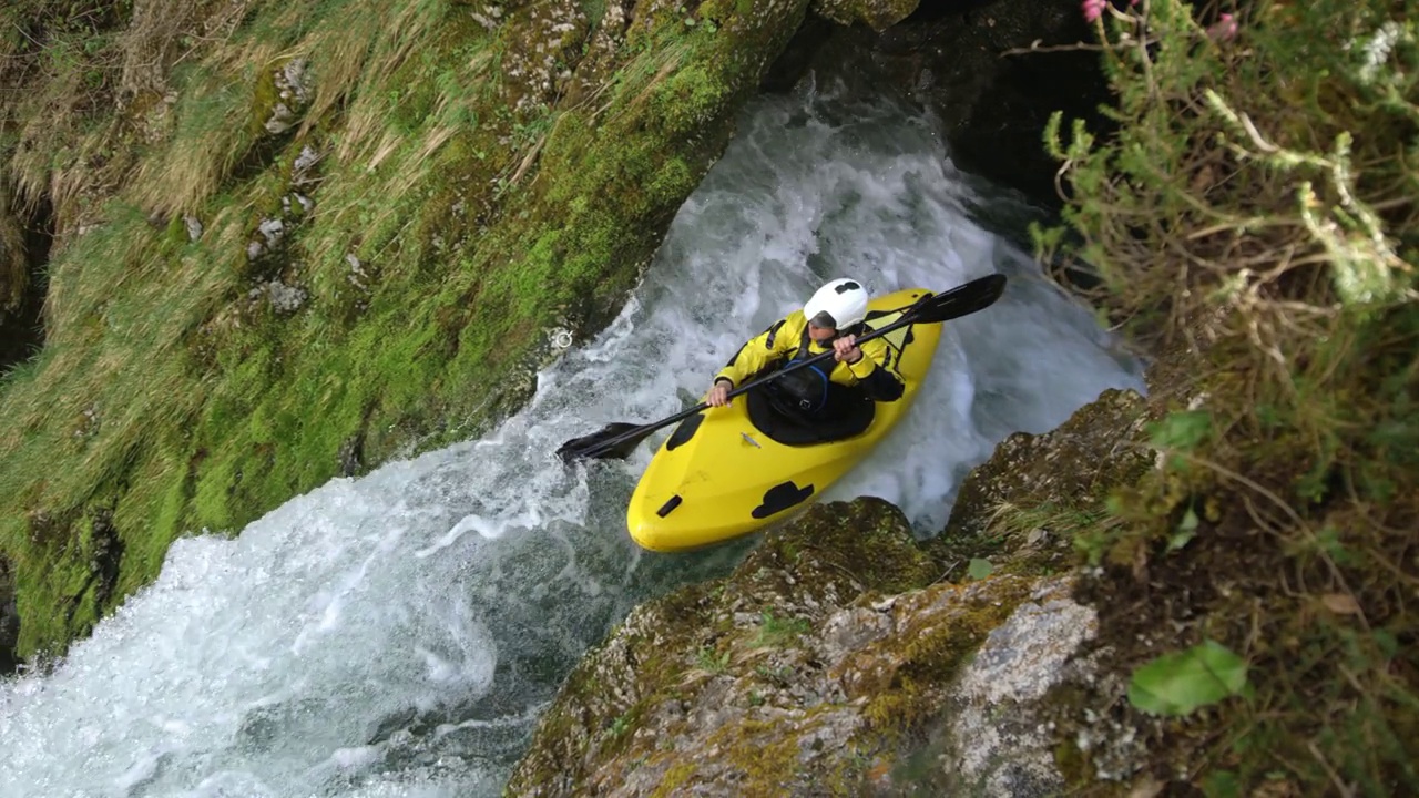 一名划黄色皮艇的SLO MO皮艇手穿过瀑布，跳进跳水池视频素材
