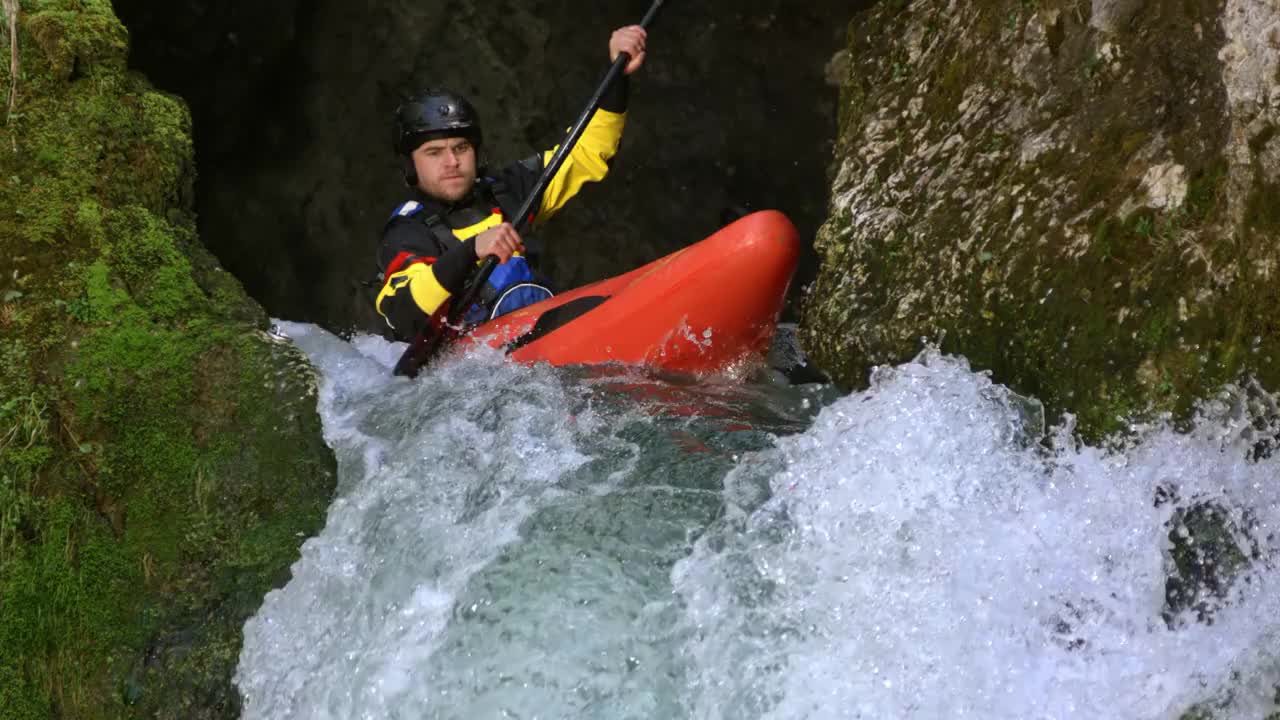 一名男子驾驶着一艘红白水皮艇，从瀑布上跳下，跳进跳水池视频下载