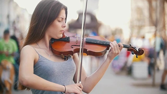 迷人的年轻女子在城市步行区拉小提琴视频素材