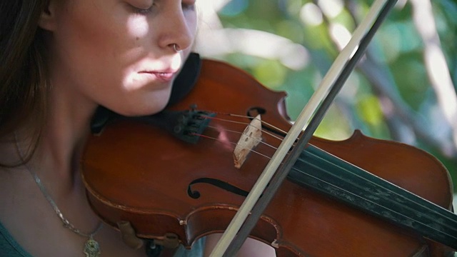 夏日里，时髦女孩在公园里拉小提琴视频素材