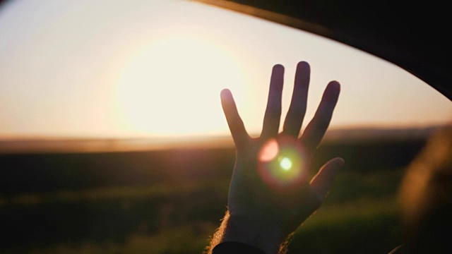 日落时一个男人的手。男人的手从车窗照在阳光下，慢动作视频素材