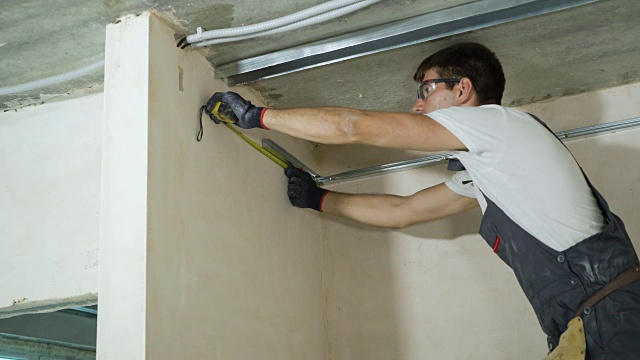 男性建筑工在室内施工现场组装金属干墙型材视频下载