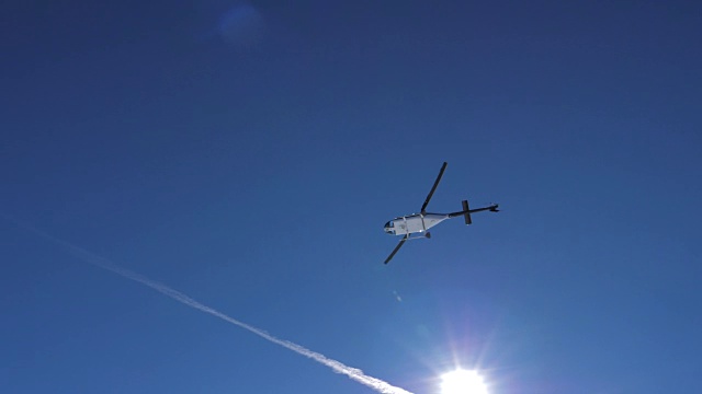 在晴朗的天气里，直升机在他头顶上方的山上低空飞行视频素材