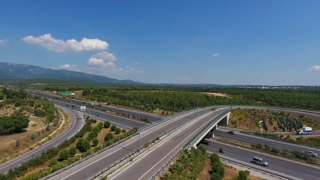 航拍过一个繁忙的高速公路十字路口蜿蜒穿过郁郁葱葱的绿色田野视频下载