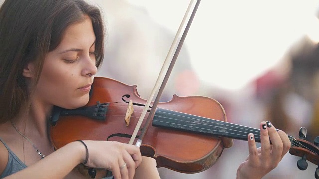 一个年轻女子在步行街拉小提琴视频素材