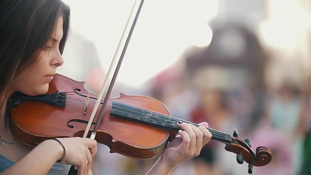 夏日里，年轻的白人女子在步行街拉着小提琴视频素材