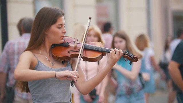 夏日里，年轻的白人女子在步行街拉着小提琴视频素材