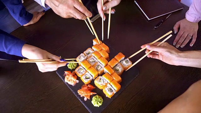餐馆桌子上的一套寿司卷。一群朋友用竹签吃寿司卷。视频素材