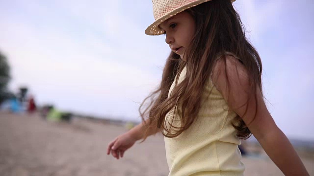 可爱的孩子戴着帽子在海滩上散步视频素材