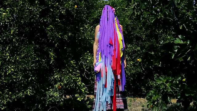 藏在橘子园五彩流苏面具后面的女人视频素材
