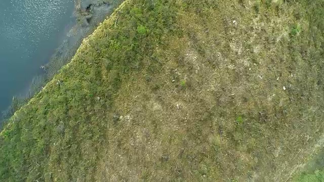 无人机飞越一个绿色崎岖的山景与湖泊，河流和郁郁葱葱的森林。视频素材