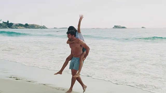 一个男人背着他的女朋友去海滩视频素材