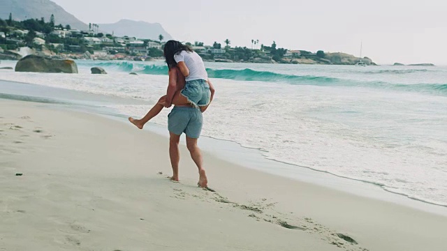 一个男人背着他的女朋友去海滩视频素材