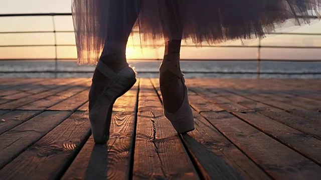 芭蕾舞女演员的脚特写，在海边的人行道上热身，踮着脚尖走路。阳光照在背景上视频素材