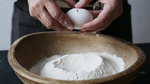 鸡蛋落在装有面粉的木碗上。视频素材