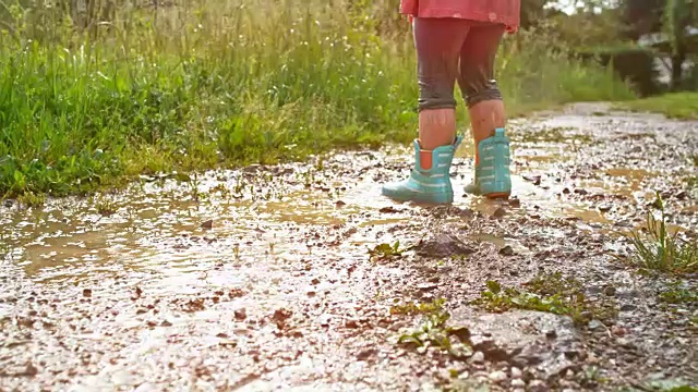 小女孩在泥泞的水坑里跳视频素材