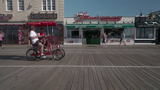 早上，人们在海洋城的木板路上骑车。视频下载