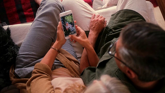一对老年夫妇在家里用智能手机看照片视频素材