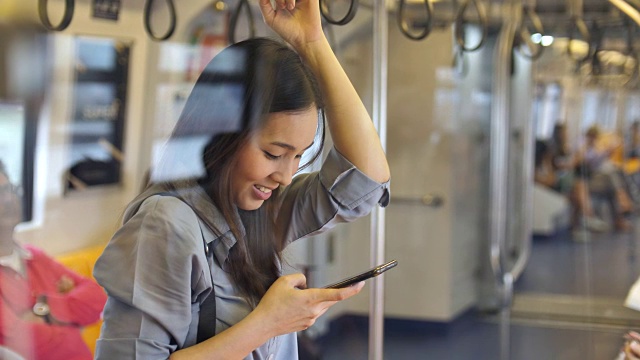 一名年轻女子在地铁上用智能手机视频素材
