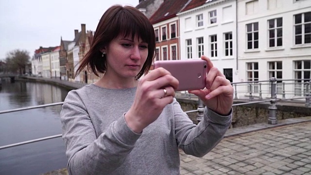 一名女游客在比利时布鲁日用智能手机拍照。慢动作视频素材