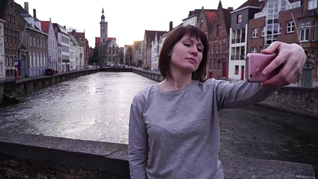 一名女游客在智能手机上自拍，背景是比利时布鲁日视频素材