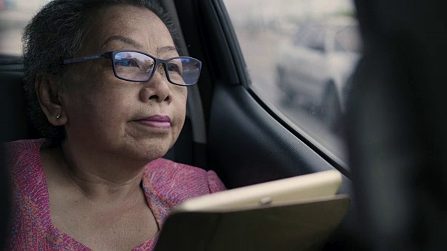 亚洲奶奶和汽车上的数字平板电脑视频素材