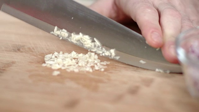 大厨用菜刀切碎蒜瓣的跟踪镜头视频素材