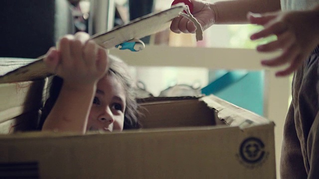 快乐的宝宝和她的妹妹在纸箱里玩。视频下载