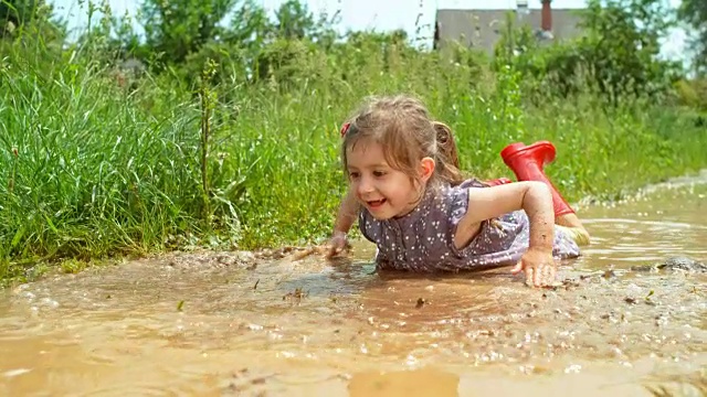 小女孩躺在水坑里，移动着她的手，好像她在游泳视频下载