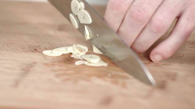 大厨用菜刀切蒜瓣的慢动作跟踪镜头视频素材