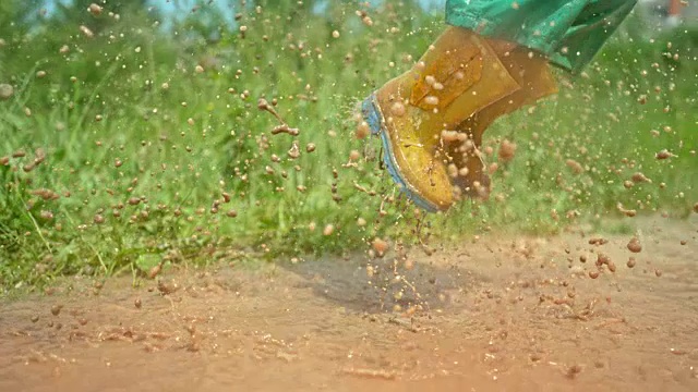 一个男孩的腿跳在水坑在他的雨靴和制造一个大水花视频下载