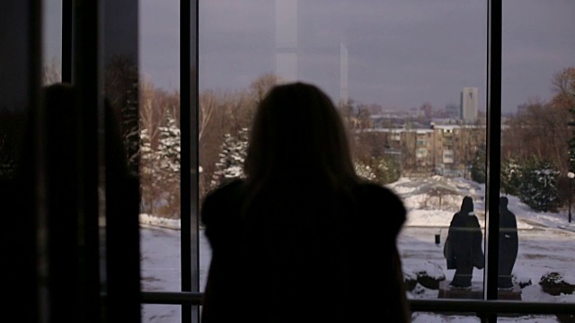 一个女孩的剪影靠近一个大窗户在冬天视频素材