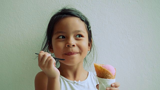 小女孩站在那里吃冰淇淋，脸上露出了快乐的表情视频下载