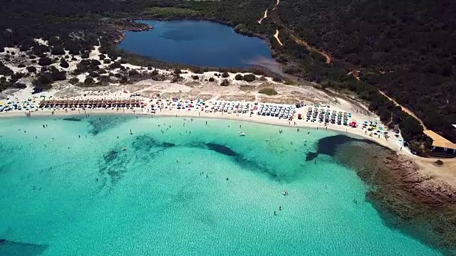 鸟瞰碧绿透明的地中海，白色沙滩上满是遮阳伞，游客们在这里放松和洗澡。意大利撒丁岛翡翠海岸(翡翠海岸)的大佩维罗湾。视频素材