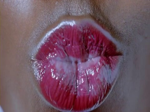 一个年轻女人的嘴的特写，涂着红色的口红和噘嘴视频下载