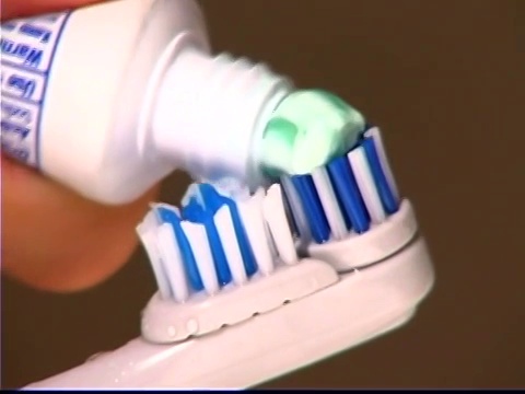 一个女孩把牙膏放到牙刷上的特写镜头。视频下载