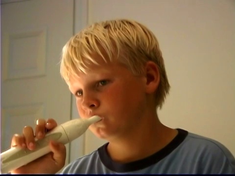 一个男孩在浴室镜子里刷牙的特写。视频素材