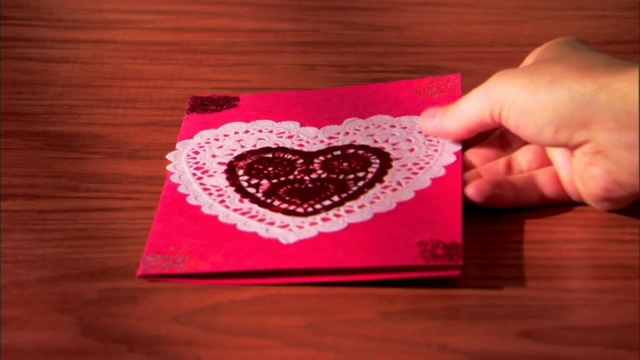 一个男人把一张自制的情人节卡片放在桌上。视频下载