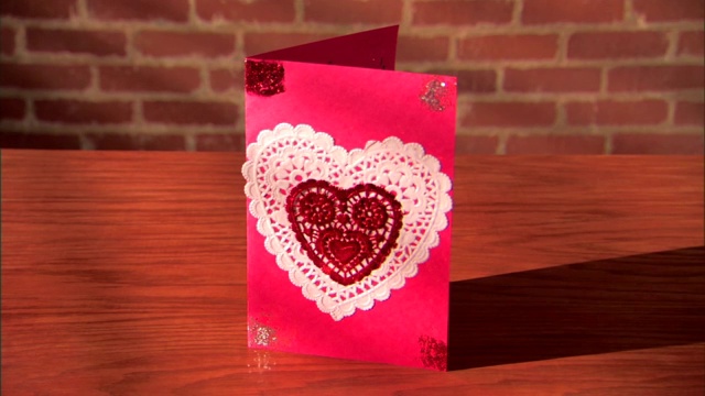 俯身在桌上放一张自制的情人节卡片。视频下载