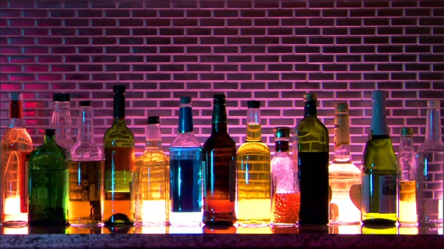 中等架集中在一排背光酒瓶上的酒吧。视频下载