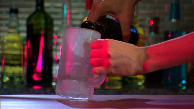 特写的调酒师吗?她用手把啤酒倒进一个冰冻的杯子里。视频下载