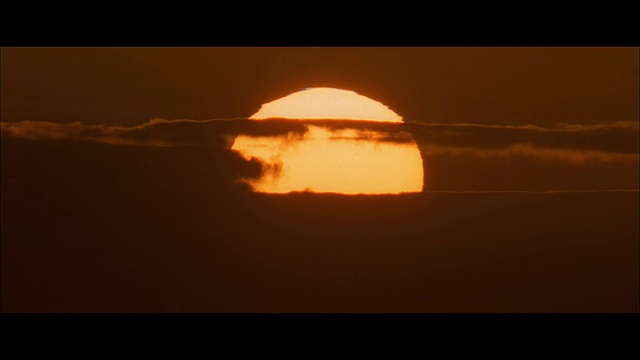 T/L太阳落在海洋和一排云，一个金色的圆盘在红色和黑暗的天空视频素材