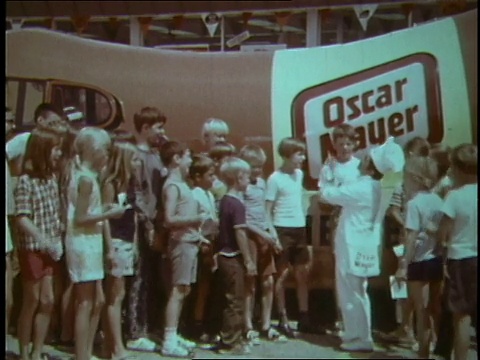 1970年，在Wienermobile外，穿着厨师服装的蒙太奇男子引导孩子们唱奥斯卡·梅尔的主题曲视频下载