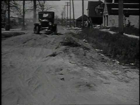 20世纪20年代蒙太奇T型车行驶在崎岖的道路上，通过小河，并通过雪/美国视频素材