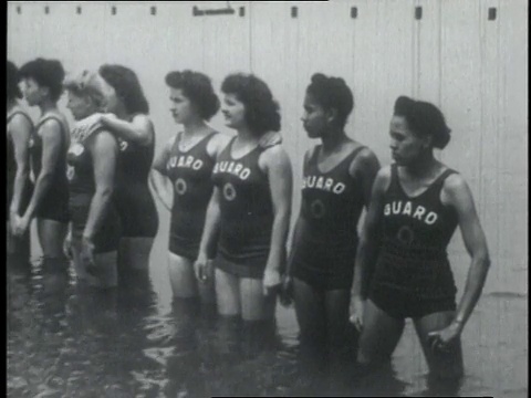 1950年美国女子运动员站在海边观看沙滩上的表演视频素材